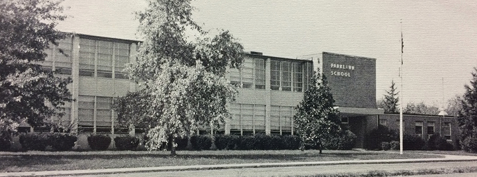 Black and white photograph of the main entrance and front of Parklawn Elementary School from our 1975 – 1976 yearbook. Unlike the image at the top of this page, the trees and shrubs appear full grown.  