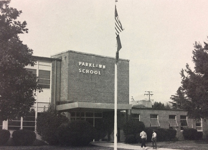 Black and white photograph of the main entrance of Parklawn Elementary School from our 1984 – 1985 yearbook. Two students are walking into the building.